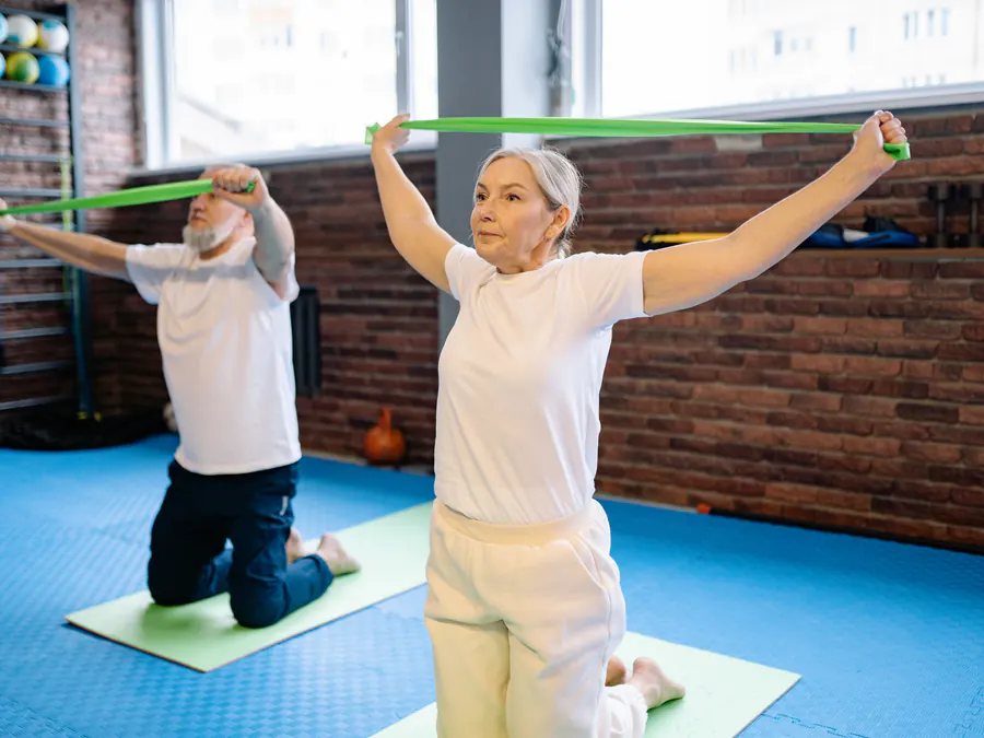 Older couple doing resistance-band strength exercises during an intensive rehabilitation session